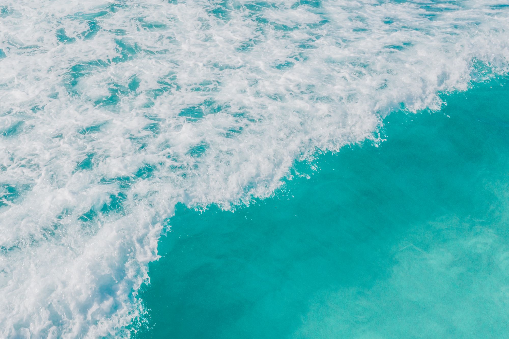 Vivid turquoise ocean water breaking into bright white foam.